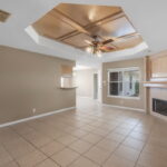 Spacious living area with tile flooring, woodburning fireplace and windows to the backyard.