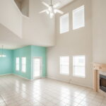 Living room with high ceiling, second living upstairs, door out to the patio and backyard.