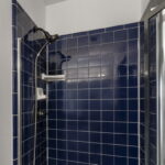 Walk-in shower is fully tiled.