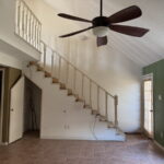Living area to back patio and stairs leading to loft bedroom.