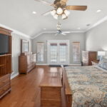 SPACIOUS primary bedroom with doors out to a private covered patio - steps from the pool and hot tub.