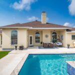 Back of home with covered patio, pool and side yard.